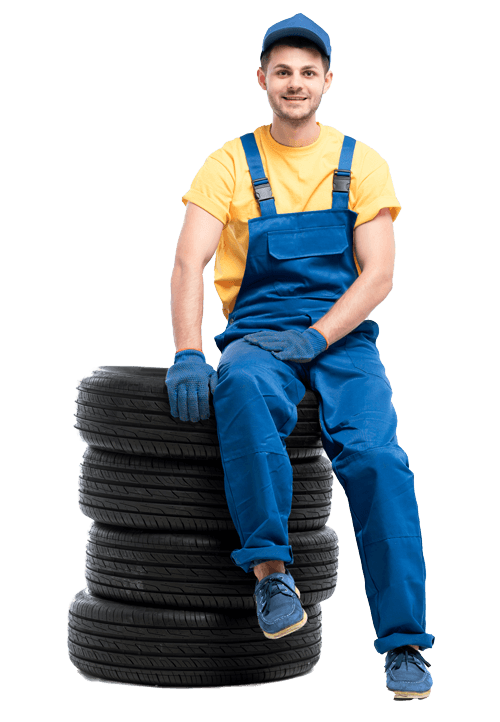 Fröhlicher Mitarbeiter der auf einem Stapel Autoreifen sitzt
